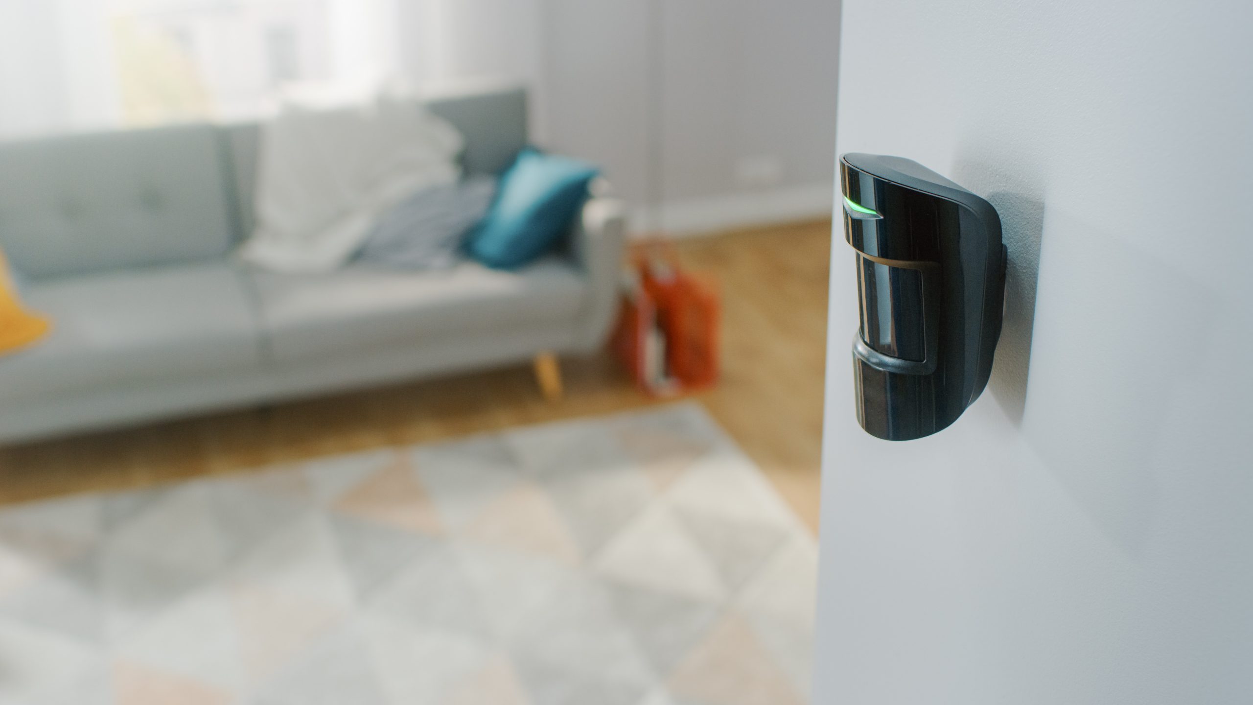 Close Up Object Shot of a Modern Movement Detector Unit on a White Wall in a Cozy Apartment in the Background. Close Up Object Shot of a Modern Movement Detector Unit on a White Wall in a Cozy Apartment in the Background.